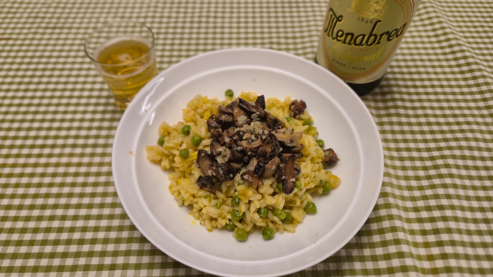 Vegan pea and mushroom risotto with creamy arborio rice, turmeric or saffron, topped with garlic-fried mushrooms and lemon.