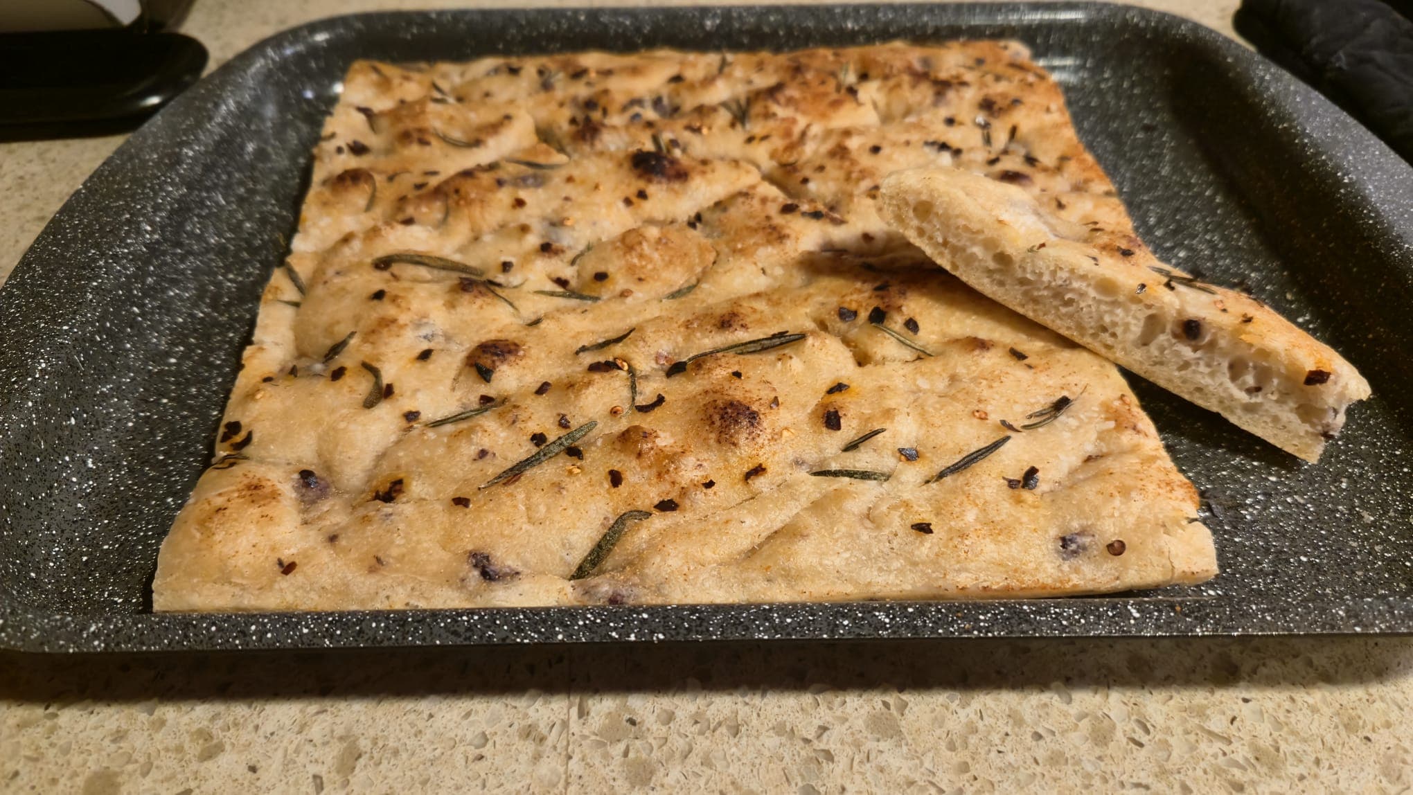 Vegan focaccia with golden crust, soft inside, topped with salt, garlic, rosemary, and optional red pepper flakes.